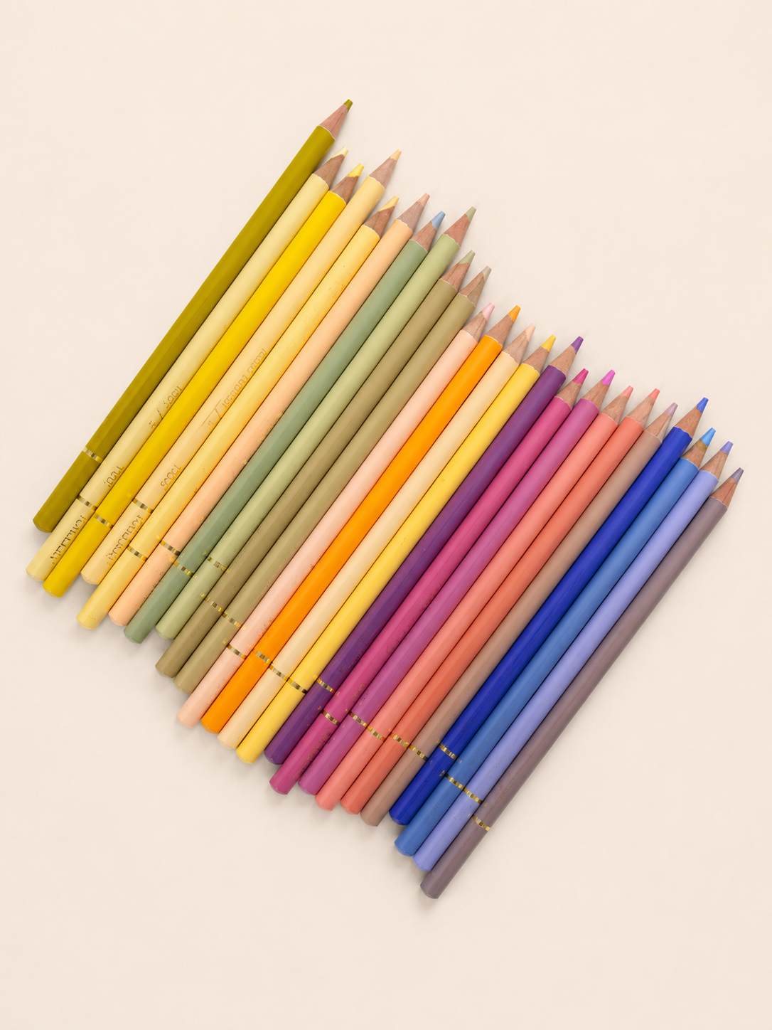 Warm toned coloured pencils in pinks, yellows and greens fanned out, included in the Zeyrem grief care package