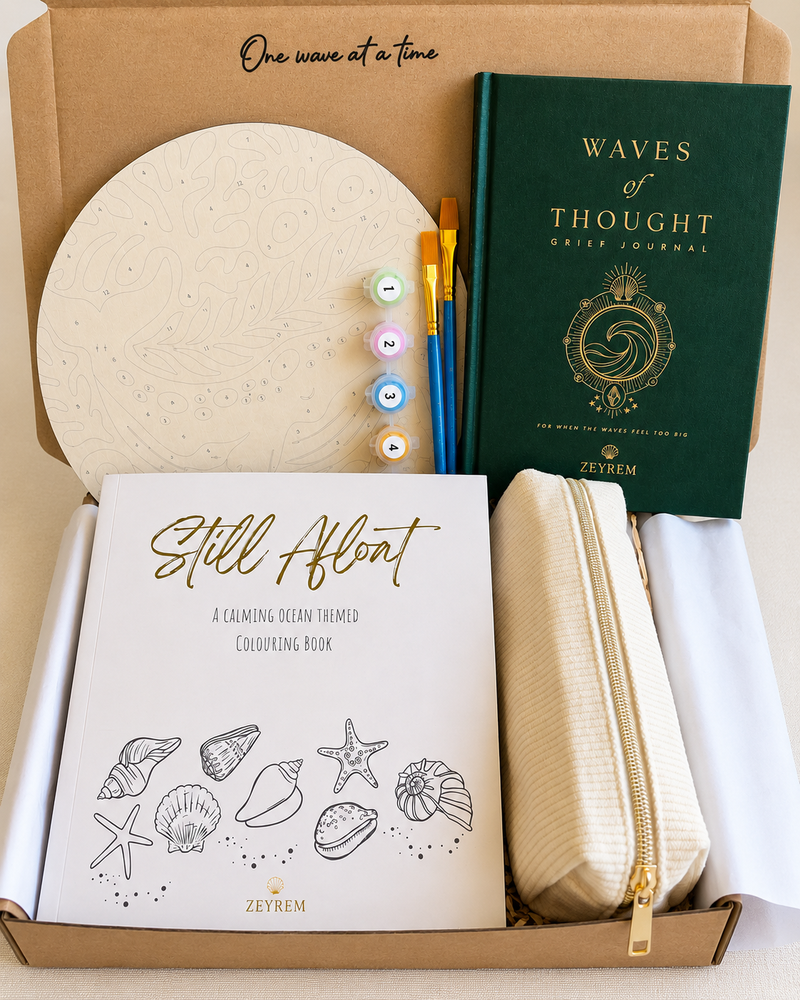 Ocean art therapy grief care package open in a Zeyrem box, with the Waves of Thought journal, Still Afloat colouring book, paint by numbers board, paints, brushes and a corduroy pencil pouch