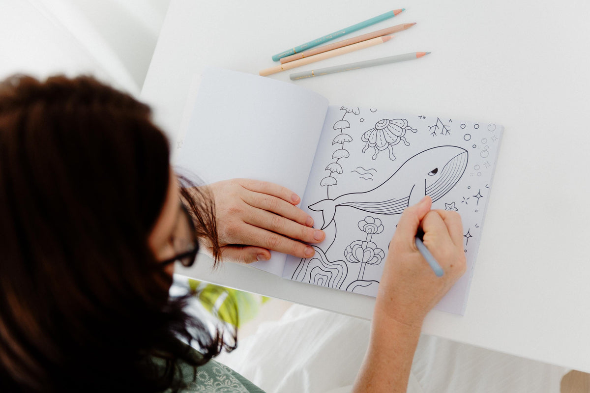 Open colouring book showing a whale illustration with coloured pencils, art therapy for grief